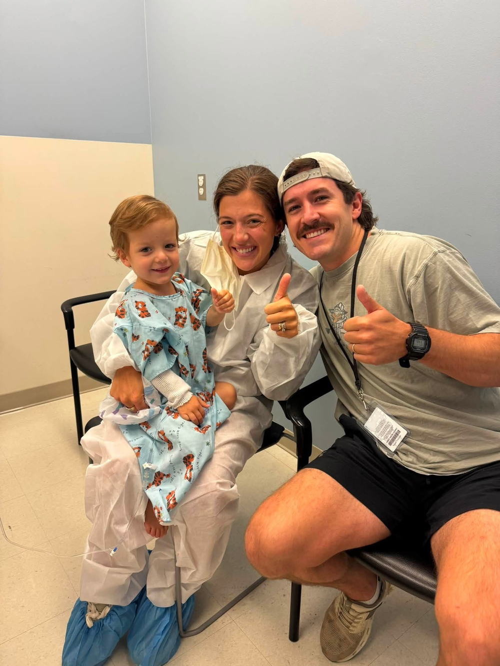 Carter with his mum and dad in the hospital, all giving a thumbs up on surgery day